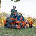 Man operating a riding lawn mower in an outdoor setting with trees and grass.