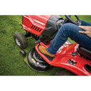Person operating a red Troy-Bilt riding lawn mower on grass