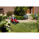 Person using a red riding lawn mower in a residential garden.